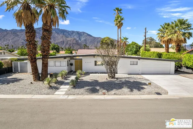 a view of a house with a yard and palm trees