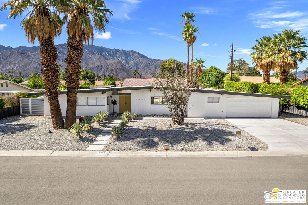 a view of a house with a yard and palm trees