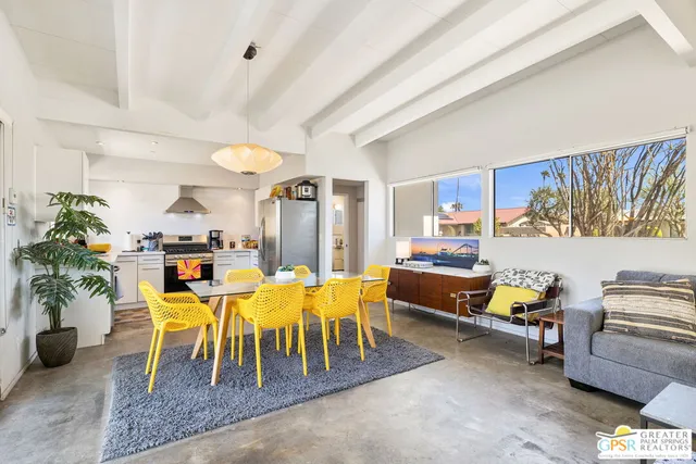 a living room with furniture and a dining table with potted plants