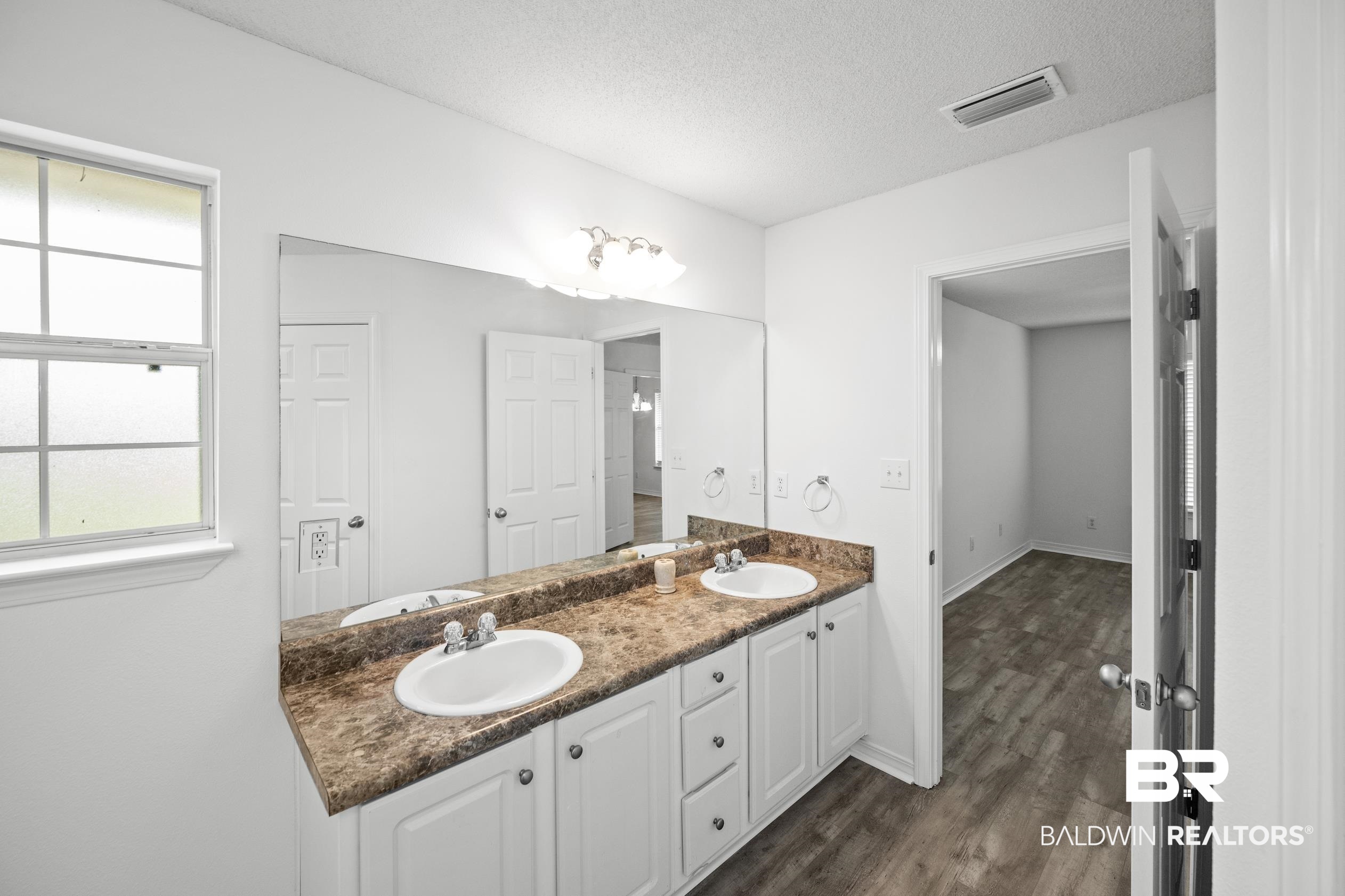 306 Monteith Oaks Drive Foley, AL 36535 - Photo 15 of 38 Bathroom featuring double vanity, dark wood-type flooring, and a textured ceiling