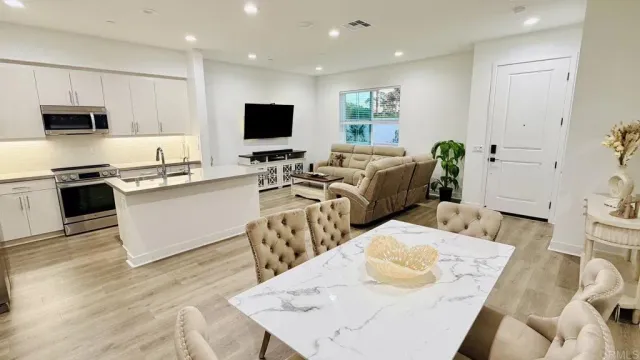 a living room with furniture a flat screen tv and kitchen view