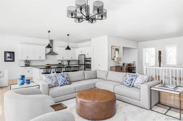 a living room with furniture kitchen view and a chandelier