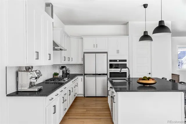 a kitchen with stainless steel appliances a stove a refrigerator and white cabinets