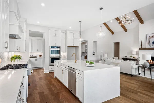 a kitchen with stainless steel appliances kitchen island granite countertop a dining table chairs and view living room
