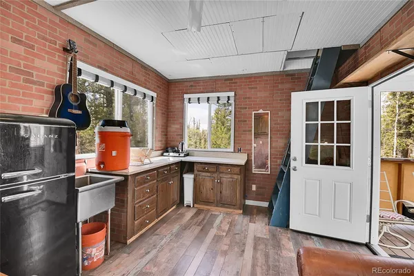 a kitchen with stainless steel appliances granite countertop a refrigerator a sink dishwasher a stove and a dining table with wooden floor