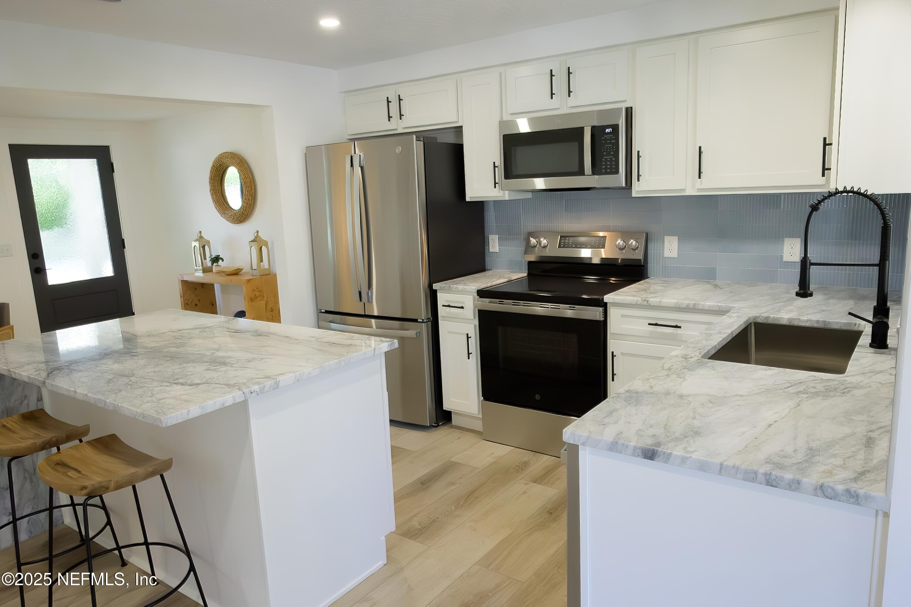 785 Triton Road Atlantic Beach, FL 32233 - Photo 10 of 46 a kitchen with stainless steel appliances granite countertop a stove a refrigerator a sink a microwave and white cabinets