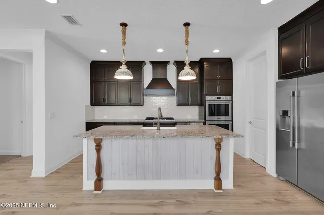 a kitchen with stainless steel appliances granite countertop a sink a stove and a refrigerator