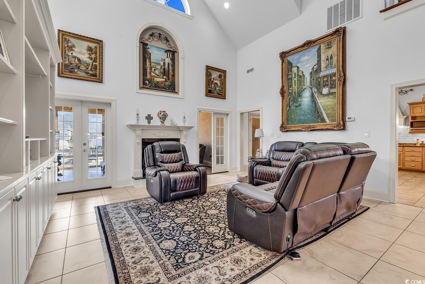 801 Bluffview Drive Myrtle Beach, SC 29579 - Photo 11 of 40 Living area featuring french doors, high vaulted ceiling, a fireplace with raised hearth, and light tile patterned flooring