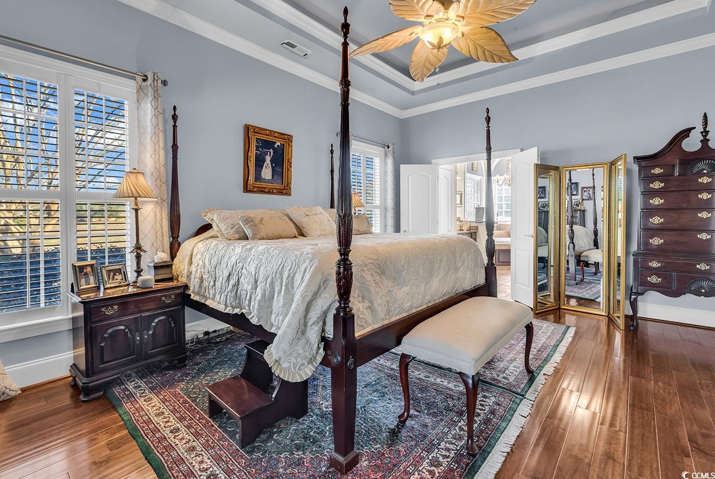 801 Bluffview Drive Myrtle Beach, SC 29579 - Photo 12 of 40 Bedroom featuring a raised ceiling, dark wood finished floors, ornamental molding, ceiling fan, and ensuite bath