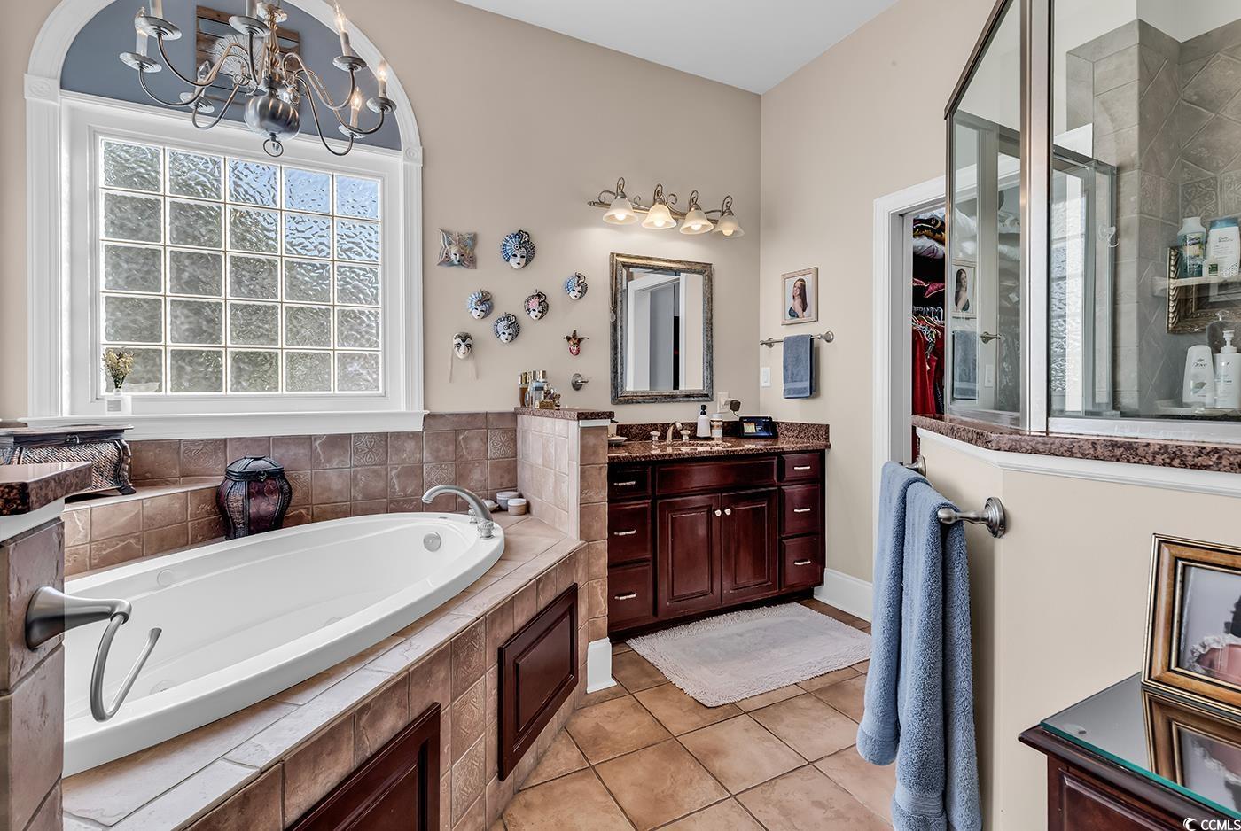 801 Bluffview Drive Myrtle Beach, SC 29579 - Photo 15 of 40 Bathroom with vanity, a chandelier, a garden tub, light tile patterned floors, and a spacious closet