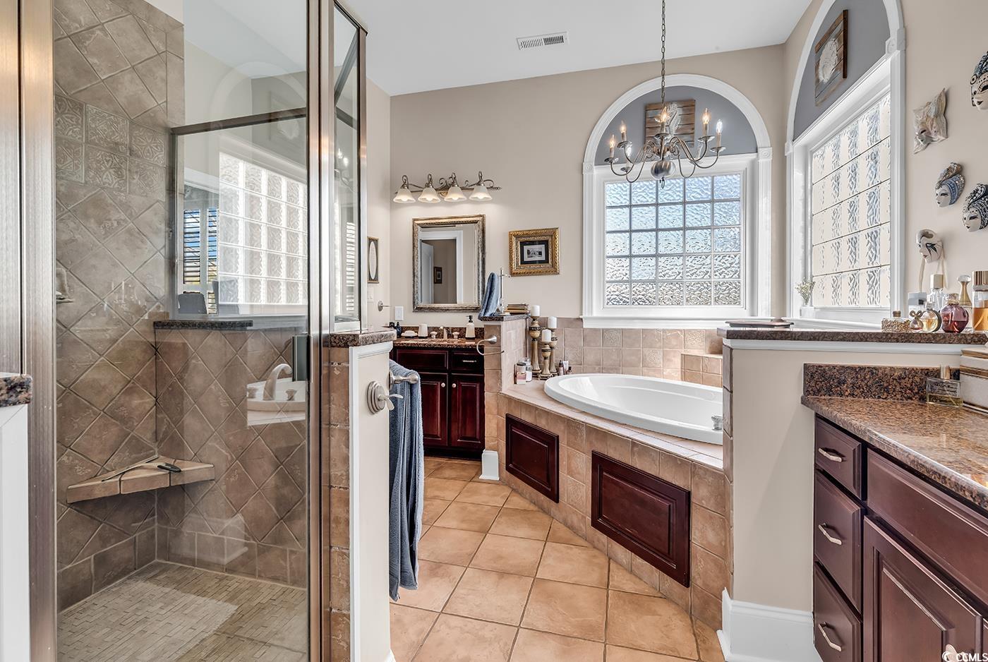 801 Bluffview Drive Myrtle Beach, SC 29579 - Photo 16 of 40 Bathroom featuring vanity, a shower stall, light tile patterned floors, a bath, and plenty of natural light