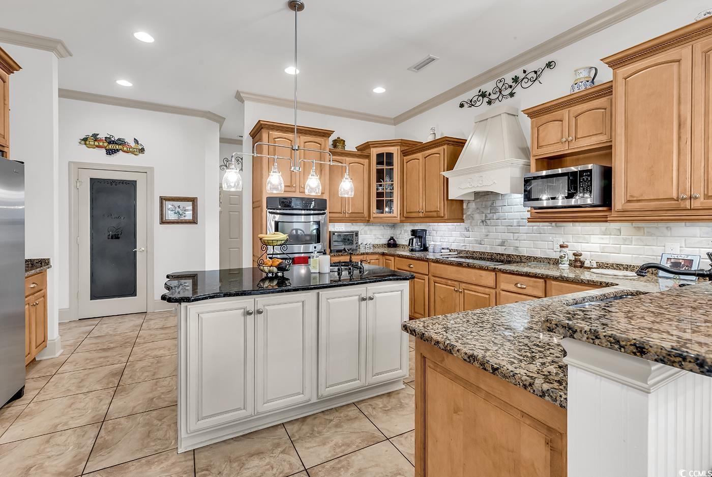 801 Bluffview Drive Myrtle Beach, SC 29579 - Photo 20 of 40 Kitchen featuring crown molding, white cabinetry, decorative light fixtures, dark stone countertops, and stainless steel appliances