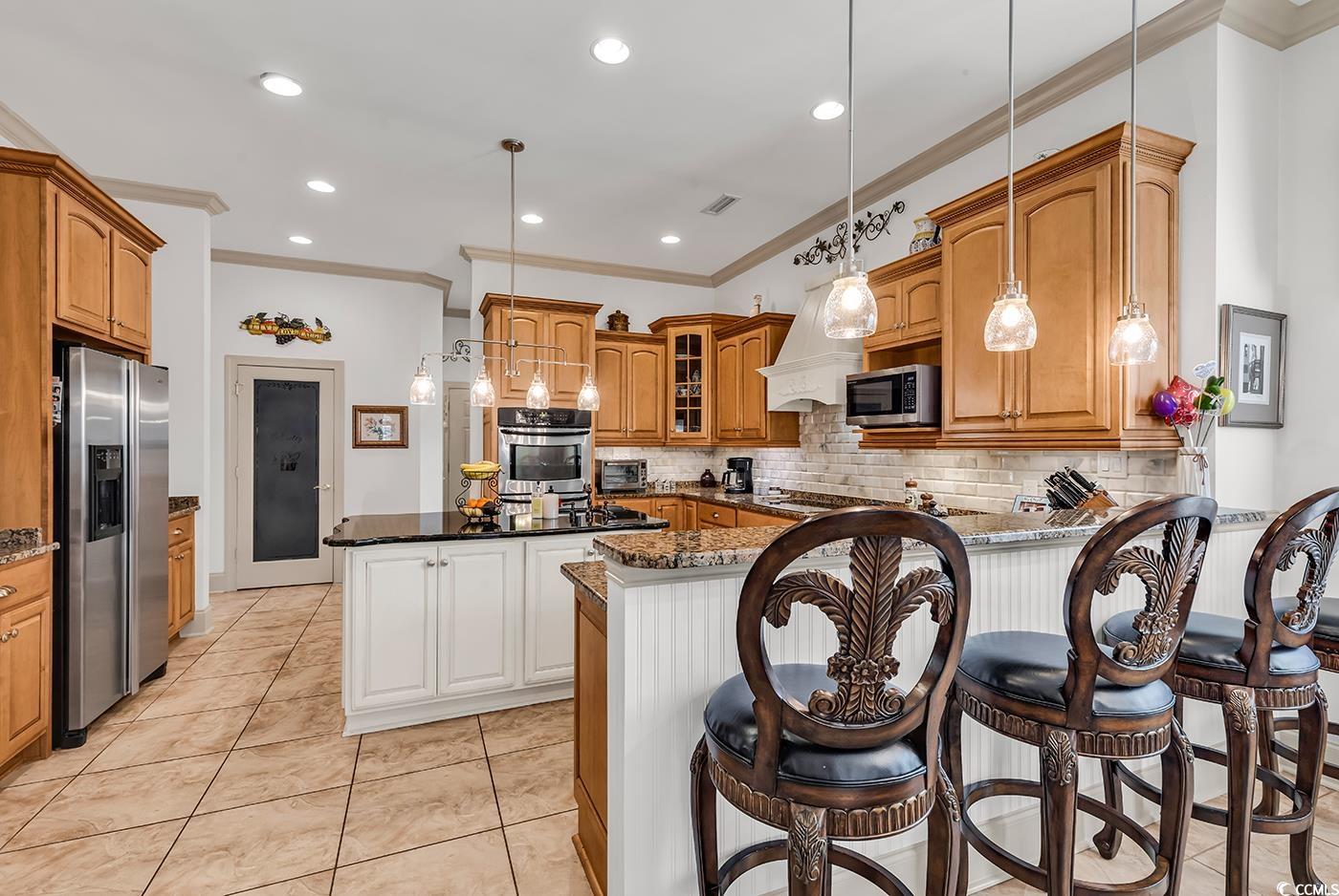 801 Bluffview Drive Myrtle Beach, SC 29579 - Photo 24 of 40 Kitchen featuring pendant lighting, ornamental molding, dark stone countertops, appliances with stainless steel finishes, and recessed lighting