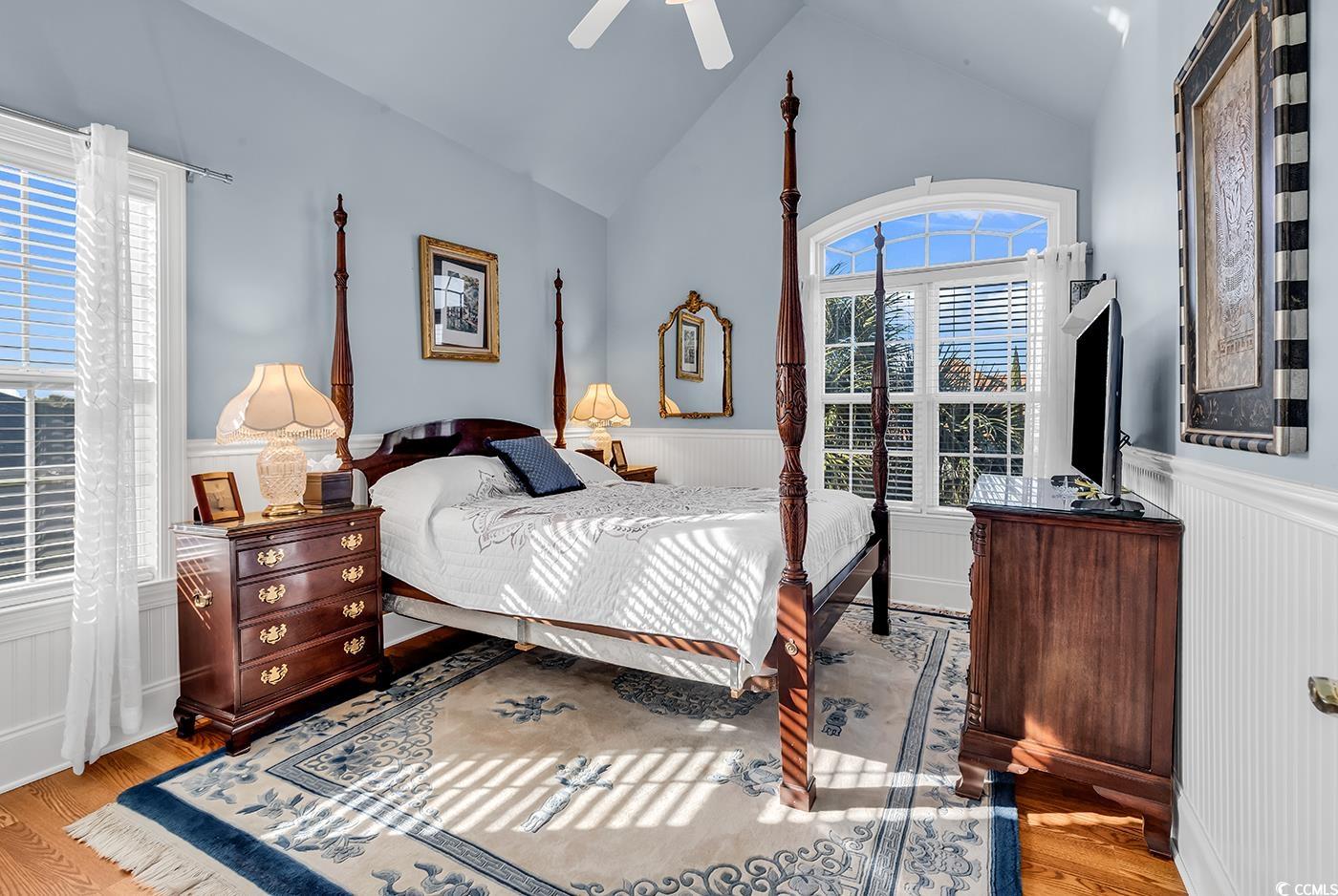 801 Bluffview Drive Myrtle Beach, SC 29579 - Photo 28 of 40 Bedroom with a wainscoted wall, lofted ceiling, wood finished floors, a decorative wall, and a ceiling fan