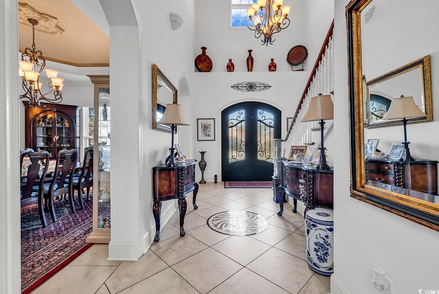 801 Bluffview Drive Myrtle Beach, SC 29579 - Photo 4 of 40 Foyer with a chandelier, arched walkways, light tile patterned floors, a high ceiling, and french doors
