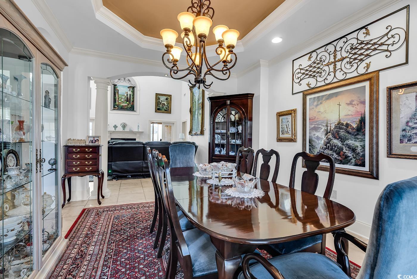 801 Bluffview Drive Myrtle Beach, SC 29579 - Photo 6 of 40 Dining space with crown molding, a tray ceiling, a chandelier, arched walkways, and light tile patterned floors
