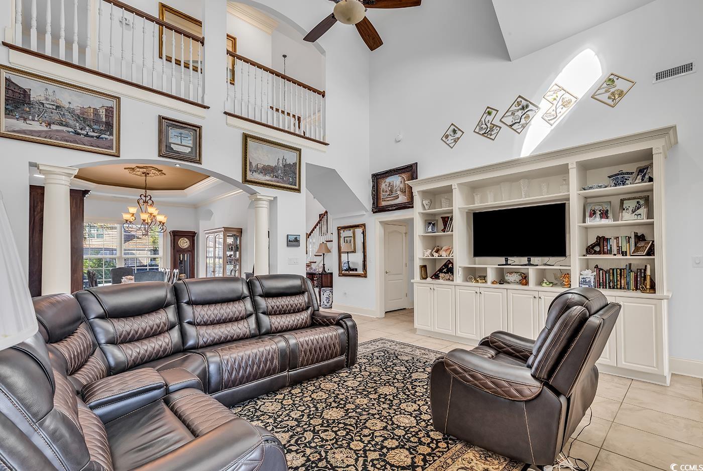 801 Bluffview Drive Myrtle Beach, SC 29579 - Photo 9 of 40 Living room with a chandelier, a towering ceiling, arched walkways, light tile patterned floors, and decorative columns
