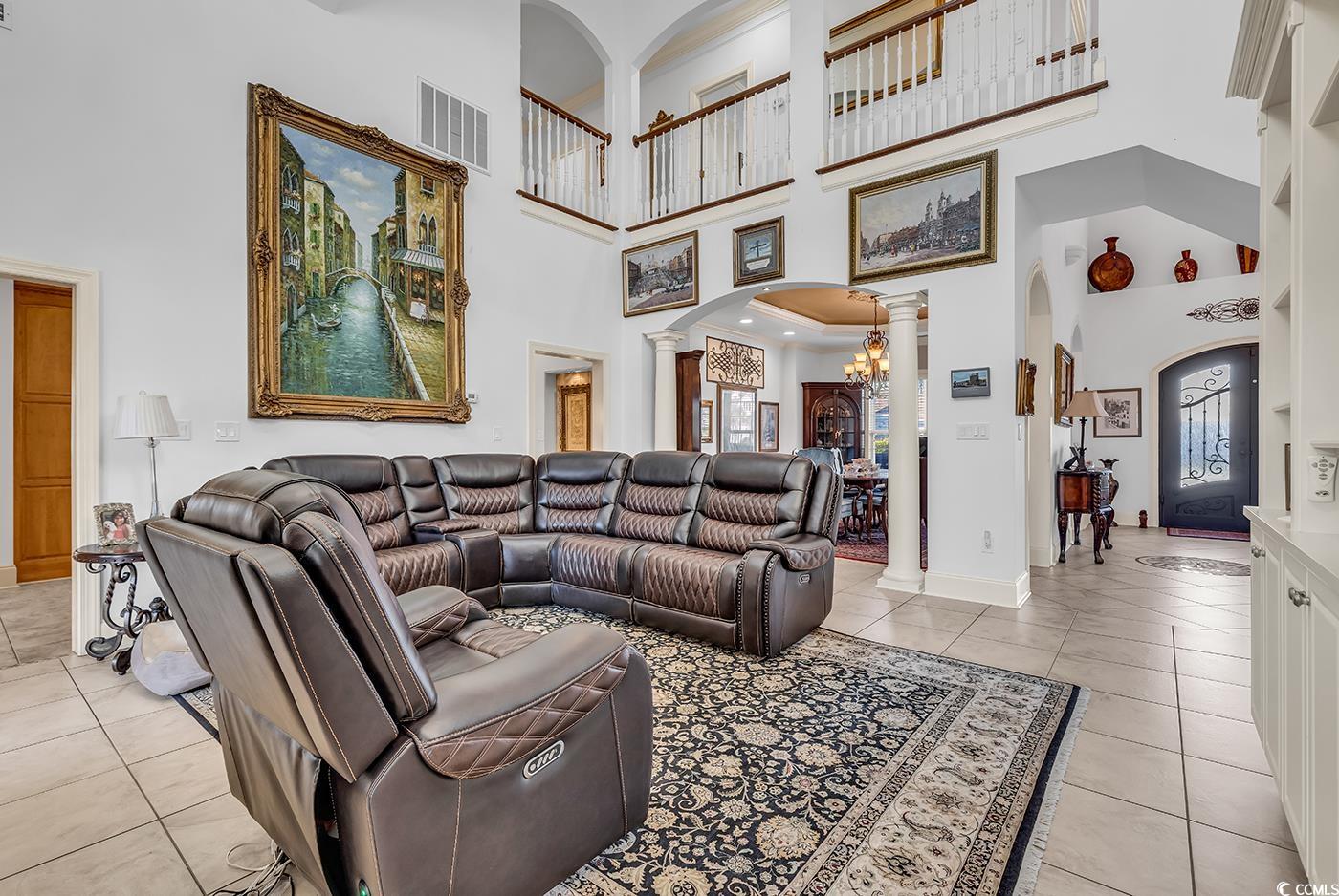 801 Bluffview Drive Myrtle Beach, SC 29579 - Photo 10 of 40 Living room featuring arched walkways, decorative columns, a high ceiling, a chandelier, and light tile patterned floors