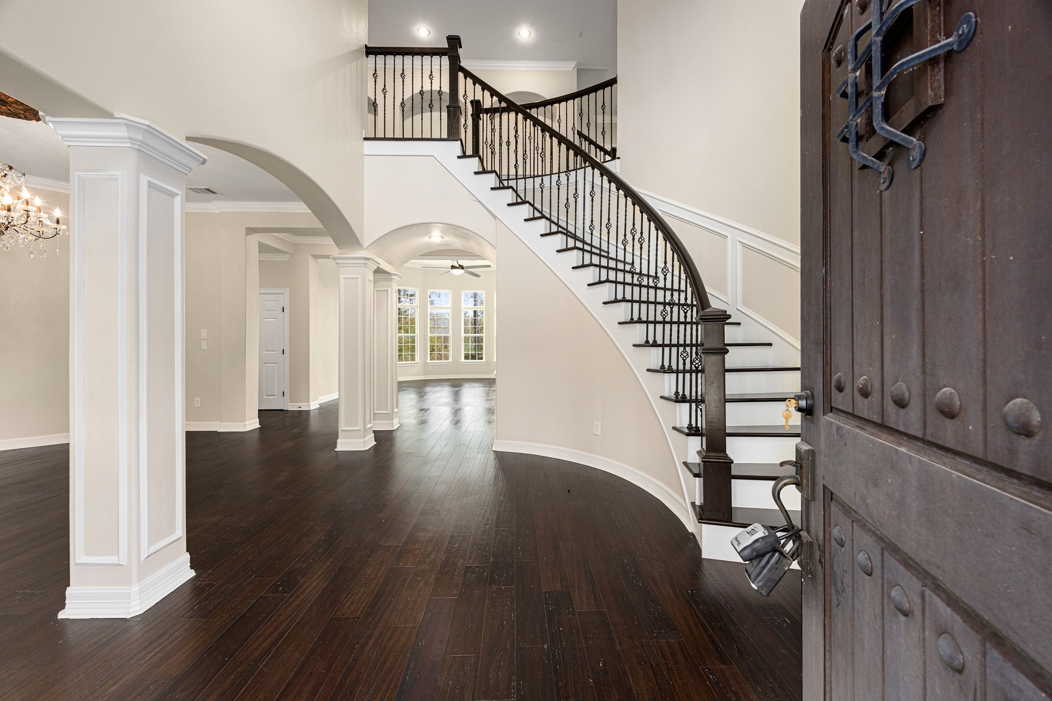 14882 Gingham Road Montgomery, TX 77356 - Photo 6 of 41 This elegant entryway features a grand, curved staircase with wrought iron railings, dark hardwood floors, and an open layout with archways leading to spacious, well-lit rooms.