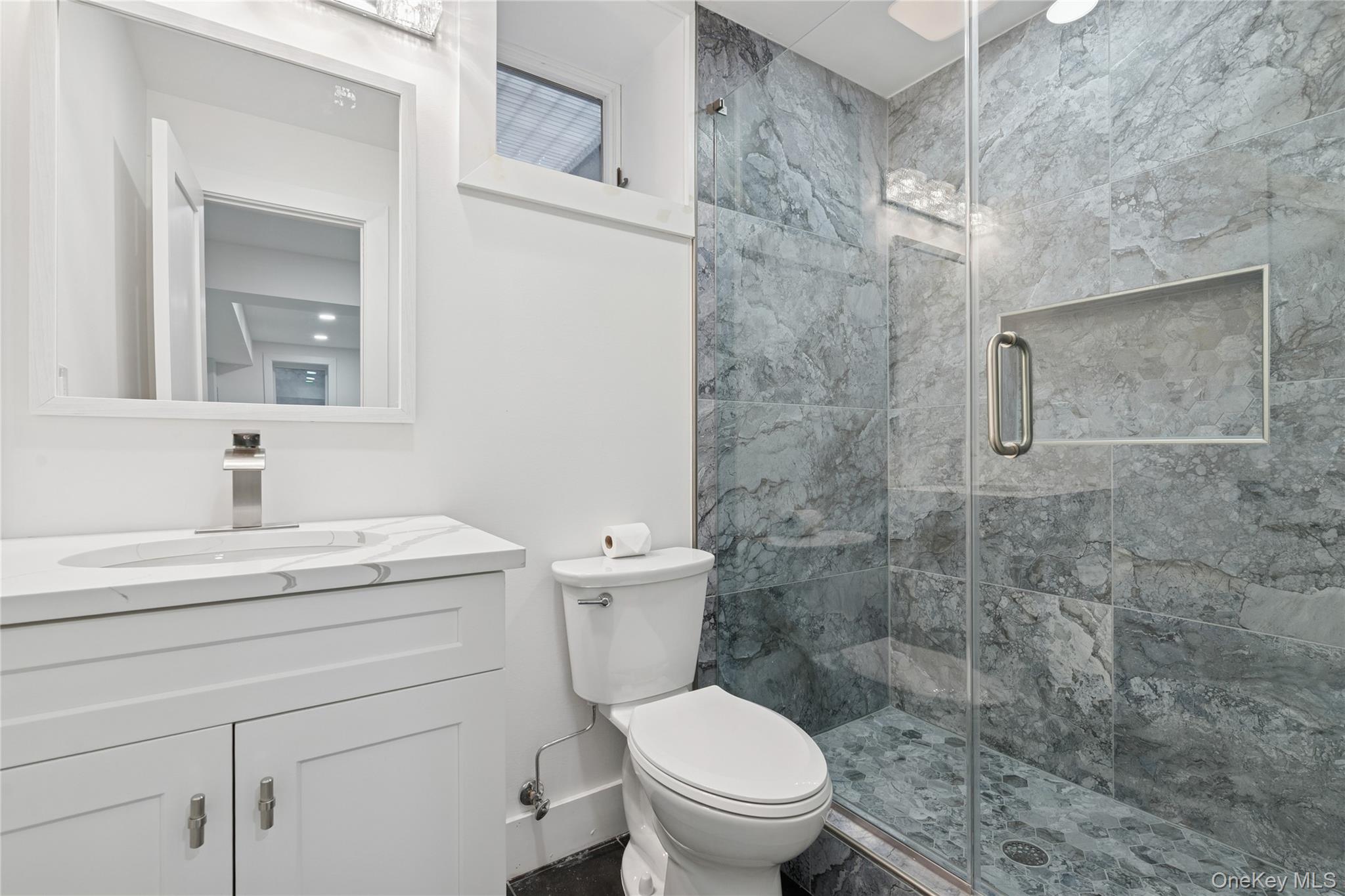 10 Sagamore Road Hampton Bays, NY 11946 - Photo 26 of 41 a bathroom with a granite countertop toilet a sink a mirror and shower