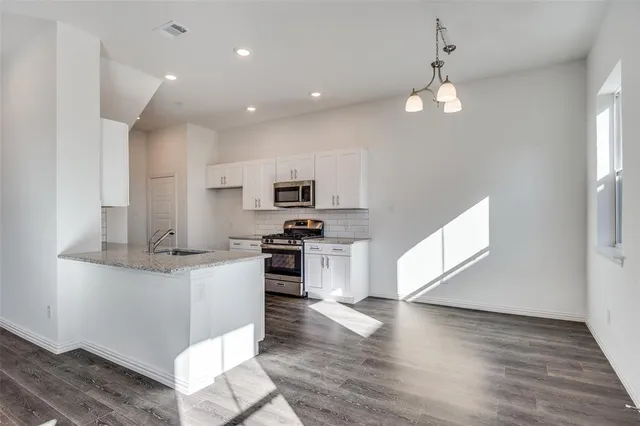 a kitchen with stainless steel appliances kitchen island granite countertop a stove a sink and a refrigerator
