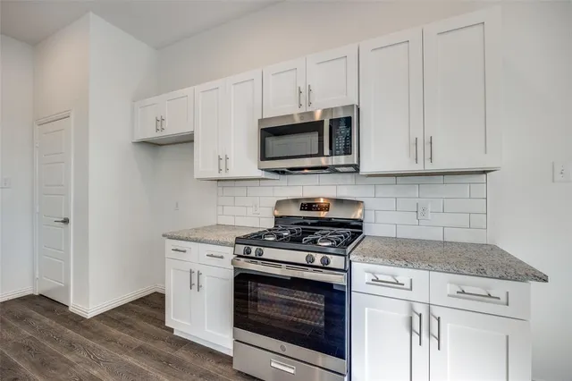 a kitchen with cabinets stainless steel appliances a sink and wooden floor