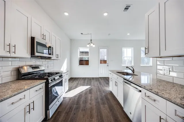 a large kitchen with stainless steel appliances granite countertop a lot of counter space and wooden floors