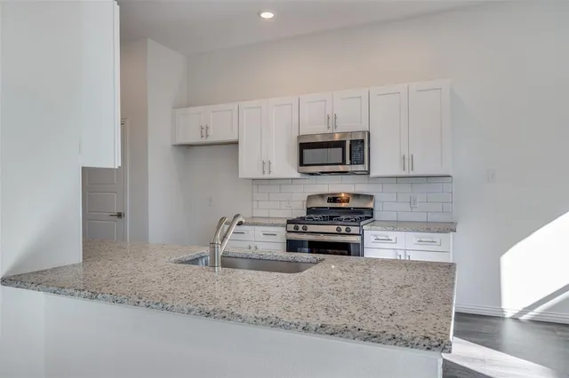 a kitchen with stainless steel appliances granite countertop a sink stove and microwave