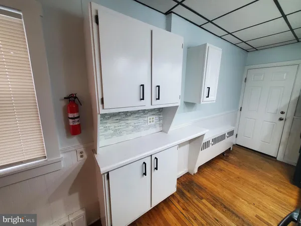 a view of a kitchen with white cabinets and wooden floor