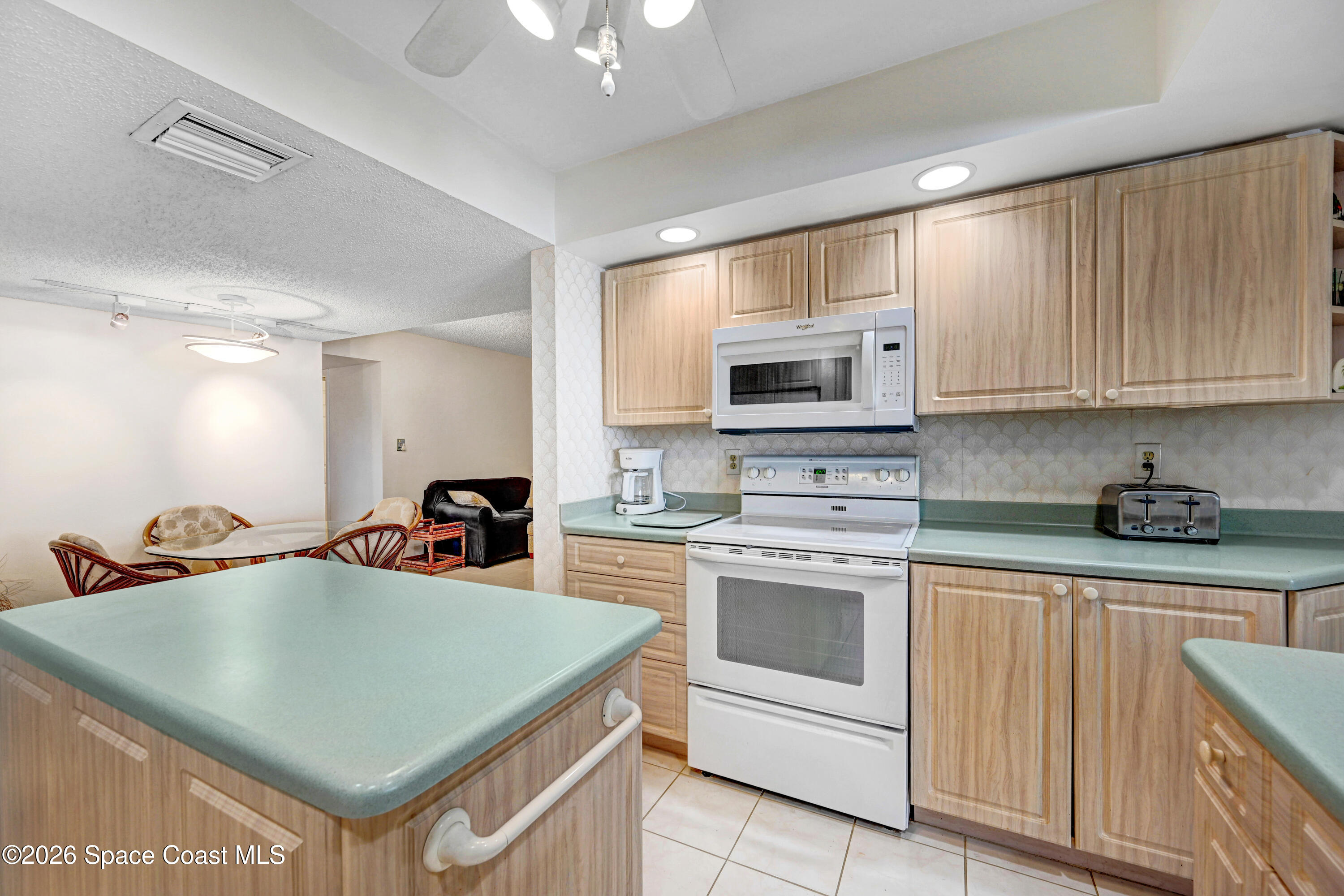 2101 Atlantic Street, Unit 533 Melbourne Beach, FL 32951 - Photo 22 of 51 a kitchen with stainless steel appliances a stove a sink a microwave a refrigerator white cabinets and wooden floor