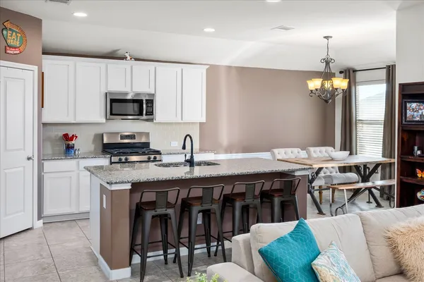 a kitchen with stainless steel appliances granite countertop a stove a sink a microwave a refrigerator a dining table and chairs with wooden floor