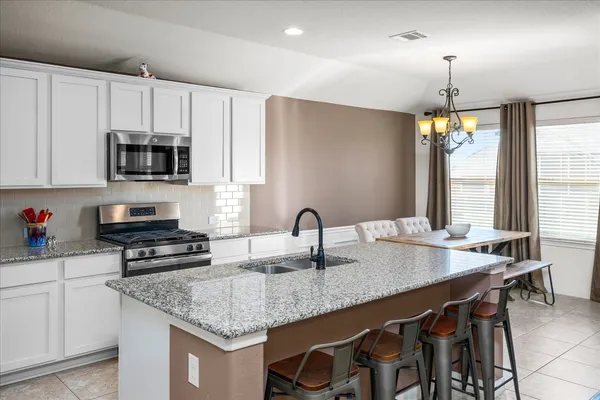 a kitchen with granite countertop a sink a stove and a microwave