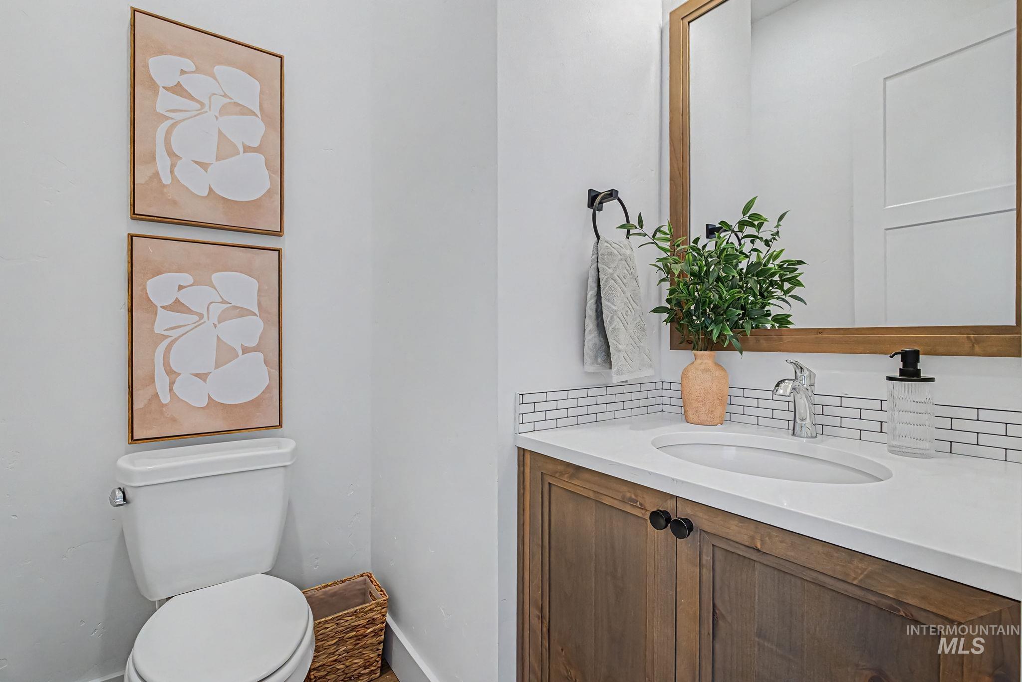 6521 South Pemberley Way Meridian, ID 83642 - Photo 12 of 42 Powder room featuring a wood-finish vanity with a white countertop and integrated sink, chrome faucet, and white subway tile backsplash
