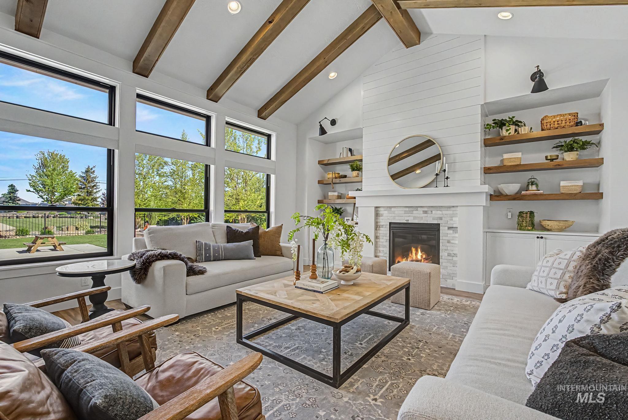 6521 South Pemberley Way Meridian, ID 83642 - Photo 13 of 42 Vaulted ceiling with exposed wood beams, expansive windows, shiplap-accented fireplace with stone surround, built-in shelving, and recessed lighting