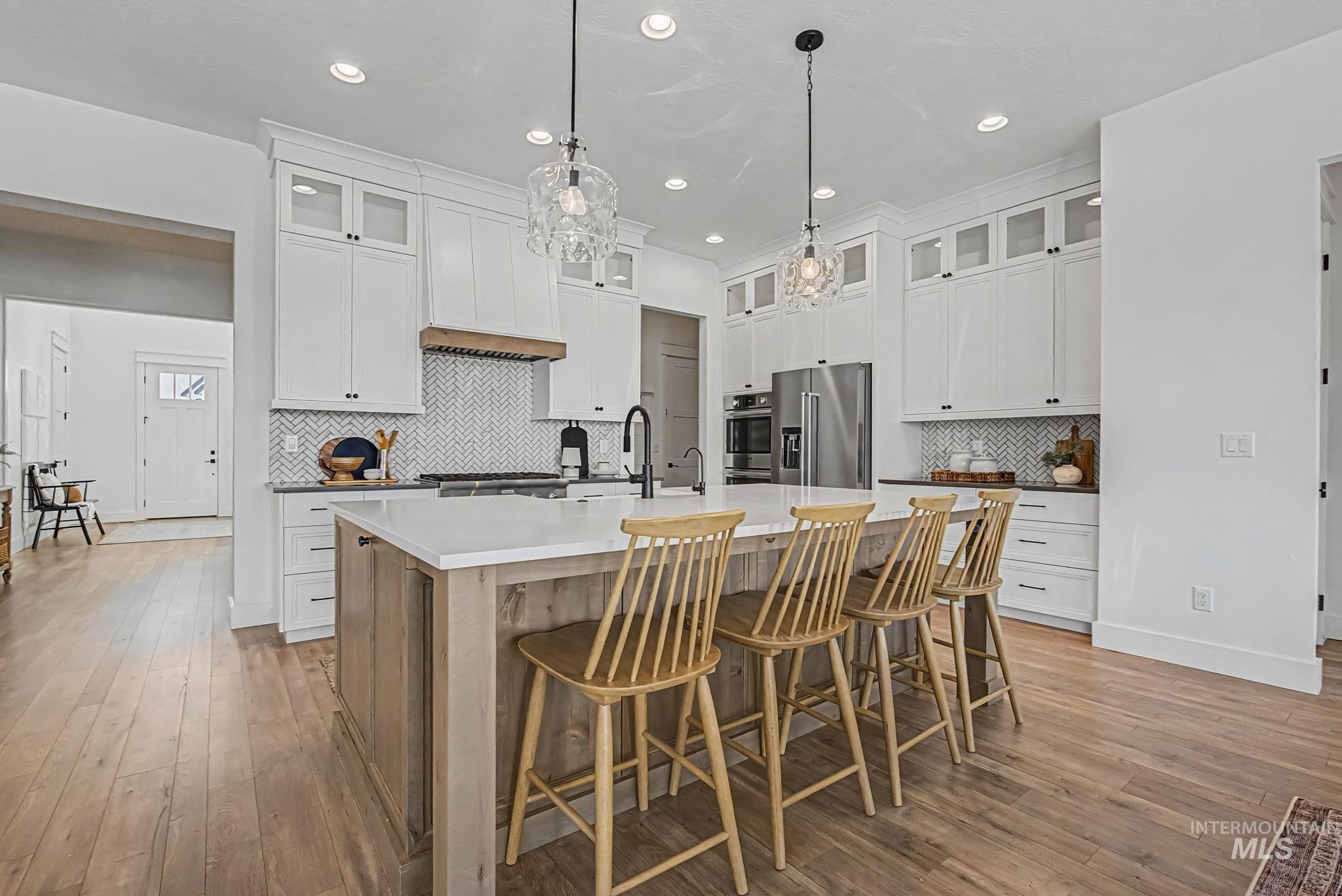 6521 South Pemberley Way Meridian, ID 83642 - Photo 16 of 42 Expansive kitchen featuring a large central island with seating, white shaker cabinetry, stainless steel appliances, and wood-finish flooring