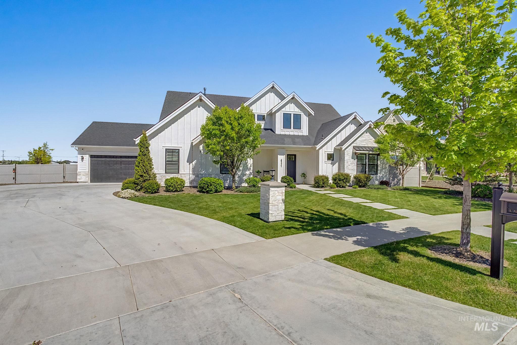 6521 South Pemberley Way Meridian, ID 83642 - Photo 2 of 42 Modern farmhouse-style exterior featuring white vertical siding, dark roof, dark-framed windows, and a black garage door