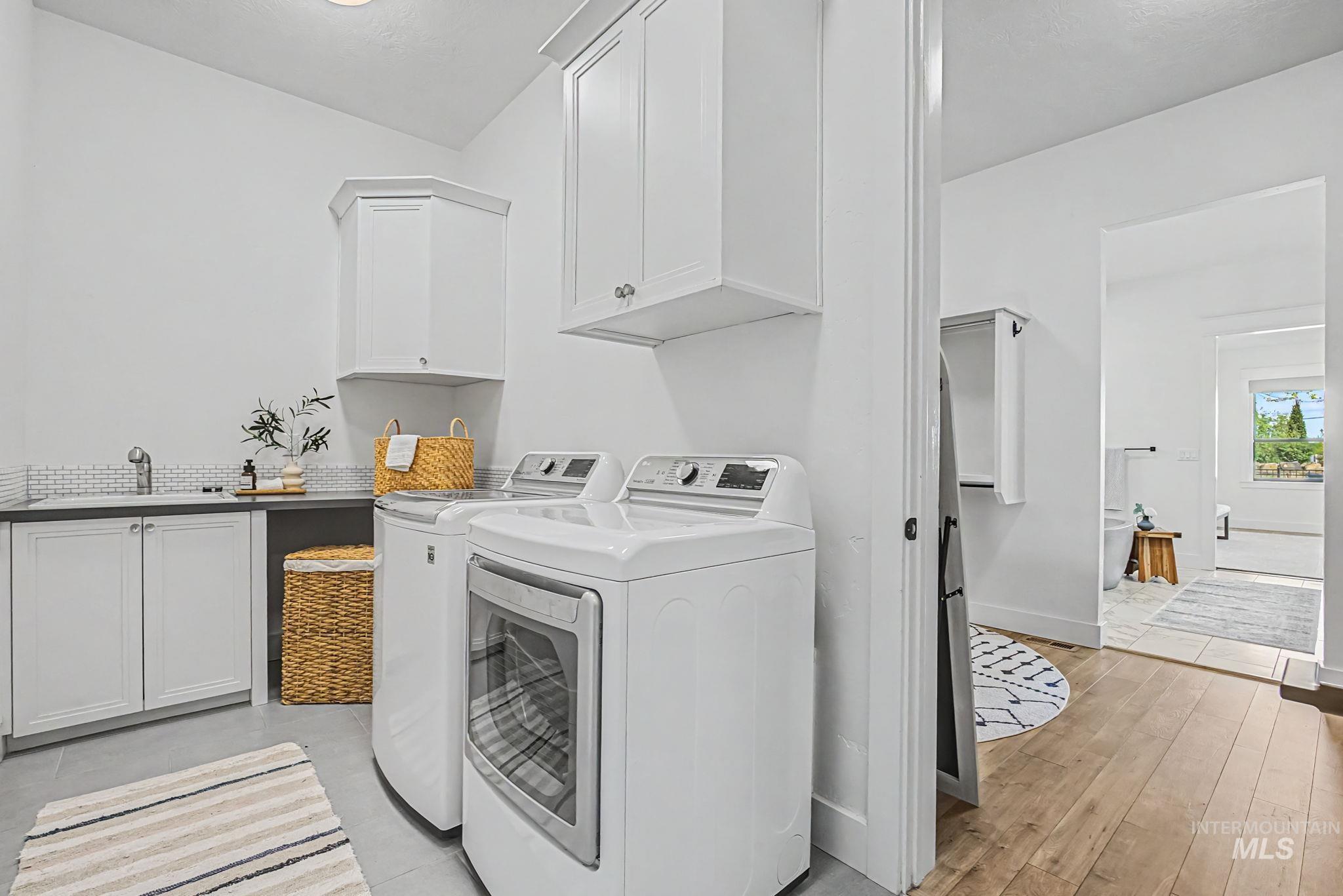 6521 South Pemberley Way Meridian, ID 83642 - Photo 21 of 42 Dedicated laundry area featuring white cabinetry, a utility sink with a tiled backsplash, and light gray floor tiling