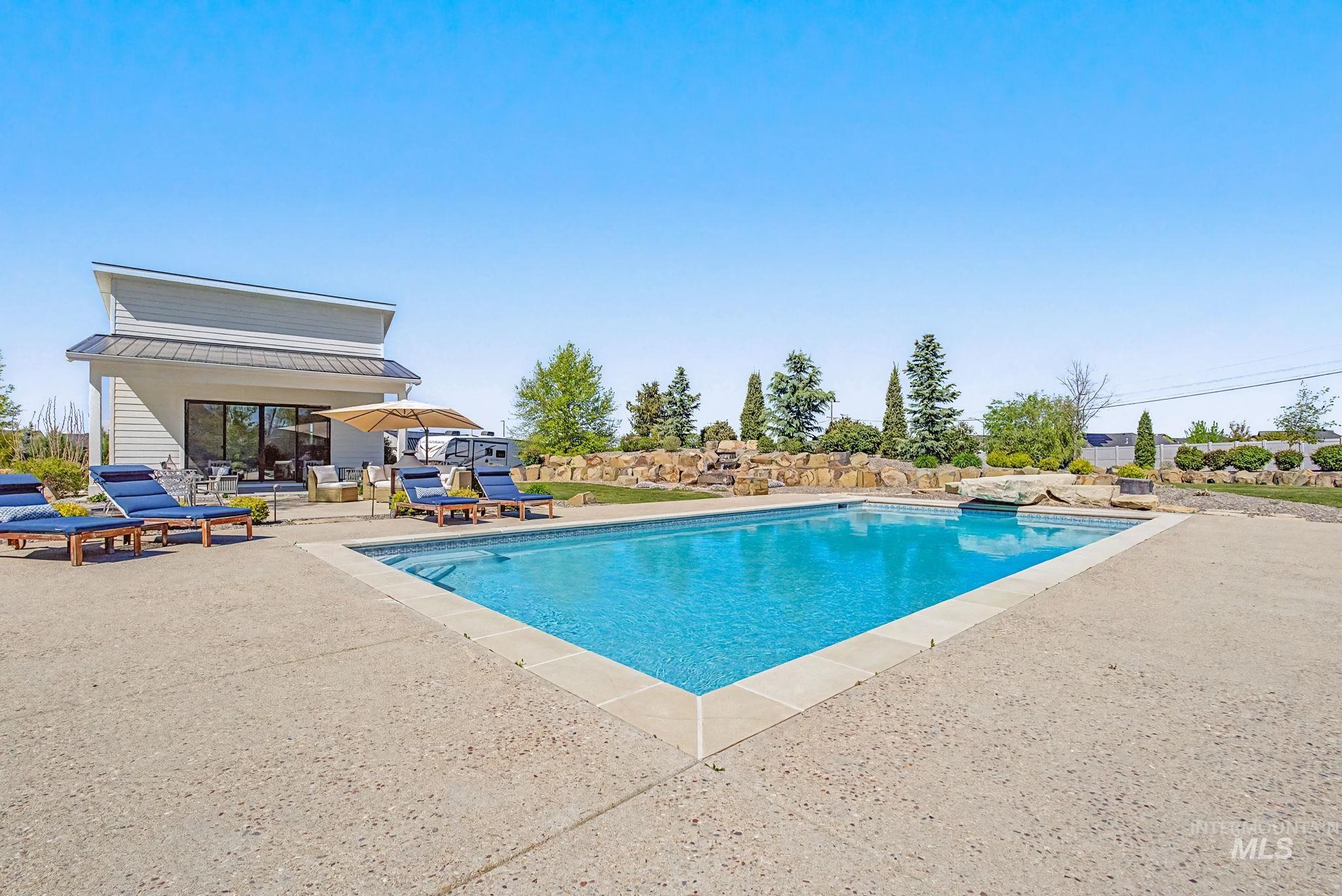 6521 South Pemberley Way Meridian, ID 83642 - Photo 34 of 42 Rectangular inground swimming pool with a stone coping border and surrounding aggregate concrete patio