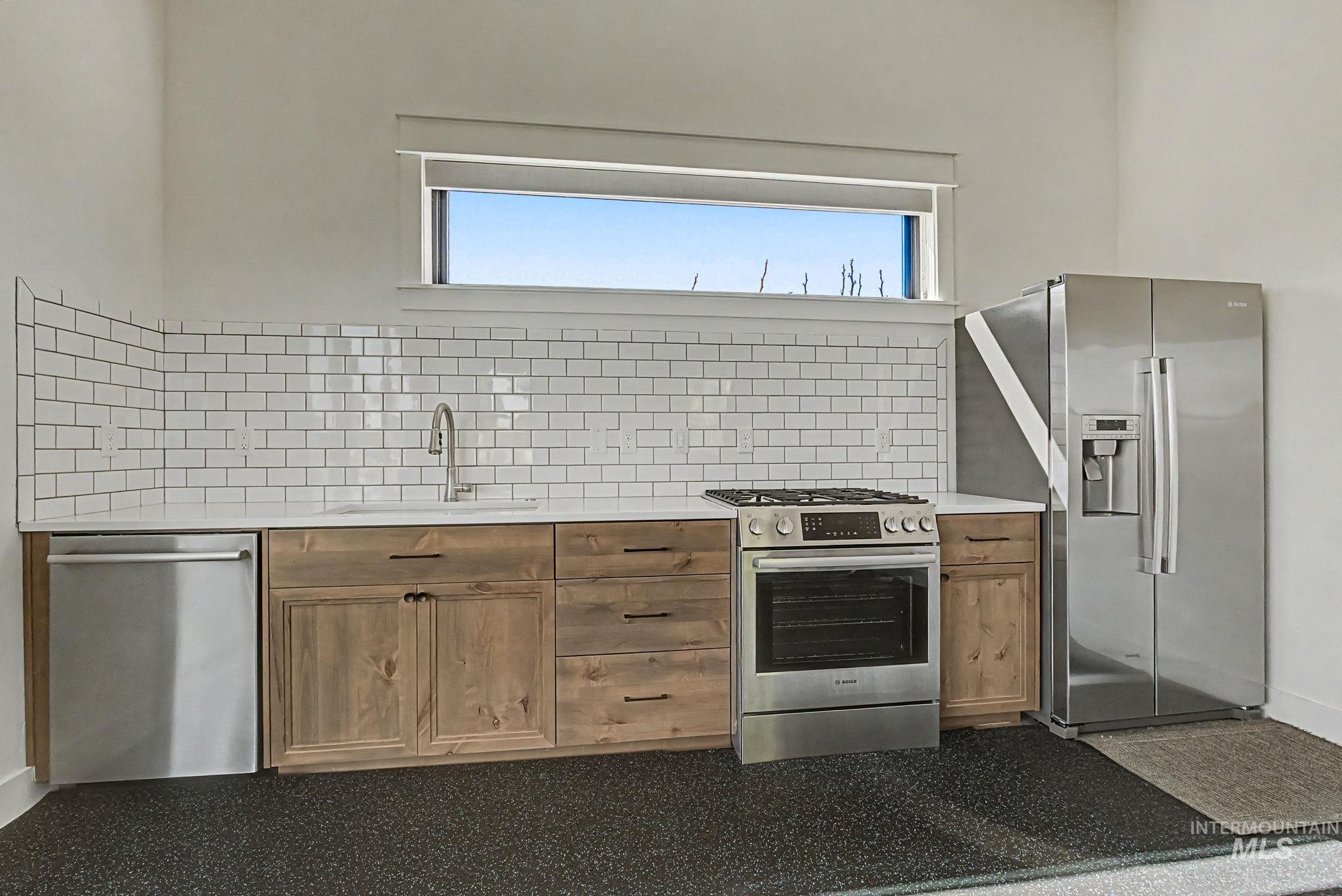 6521 South Pemberley Way Meridian, ID 83642 - Photo 39 of 42 Kitchenette featuring stainless steel appliances, a white subway tile backsplash, light wood-finish cabinetry, and a countertop with an integrated sink