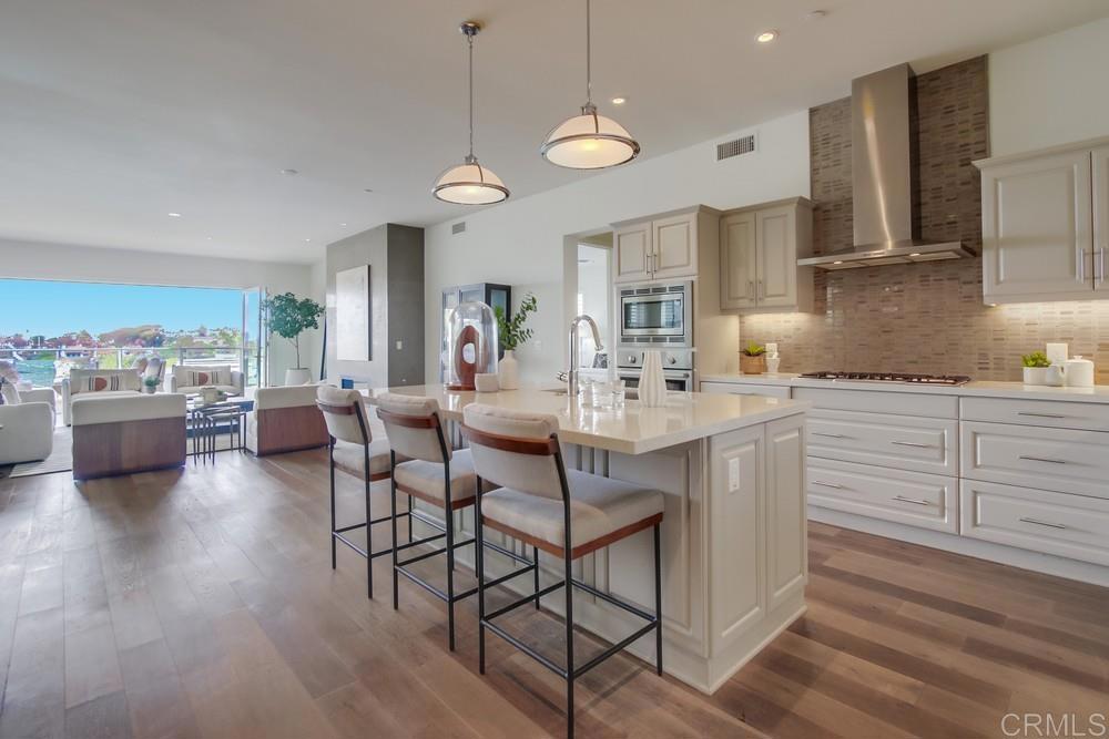2333 Ocean Street Carlsbad, CA 92008 - Photo 10 of 67 a kitchen with stainless steel appliances kitchen island granite countertop a stove a sink a dining table and chairs with wooden floor