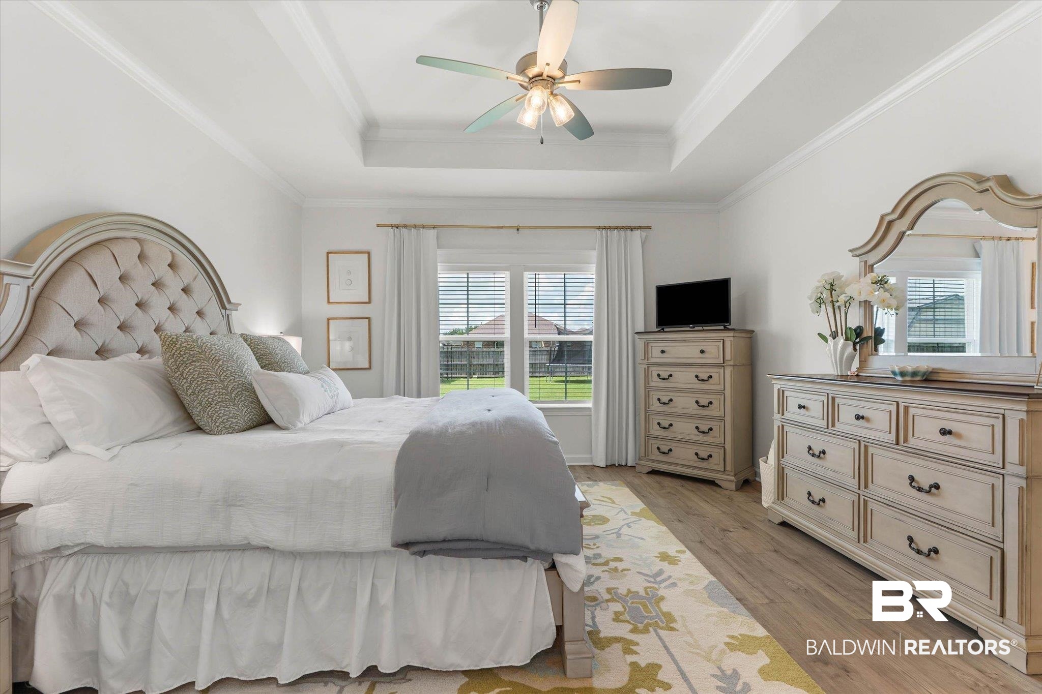 9074 Moses Way Theodore, AL 36582 - Photo 23 of 52 Bright bedroom featuring wood-finish flooring, a tray ceiling, and a ceiling fan