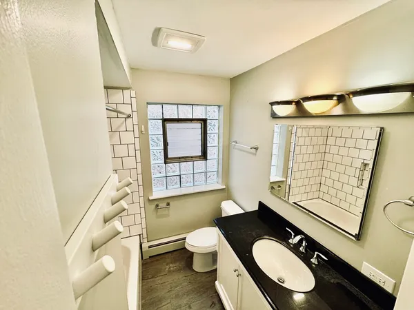 a bathroom with a granite countertop toilet sink and mirror