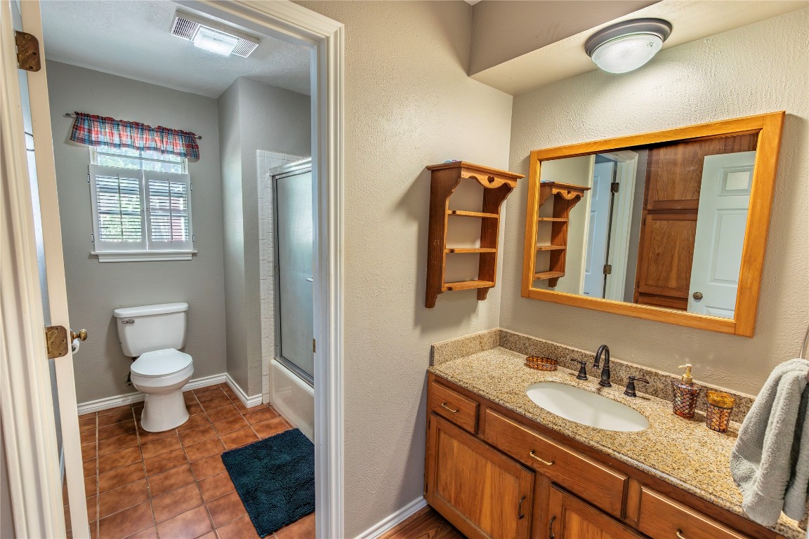636 Deer Run Road Bellville, TX 77418 - Photo 9 of 23 a bathroom with a granite countertop sink a toilet and a large mirror