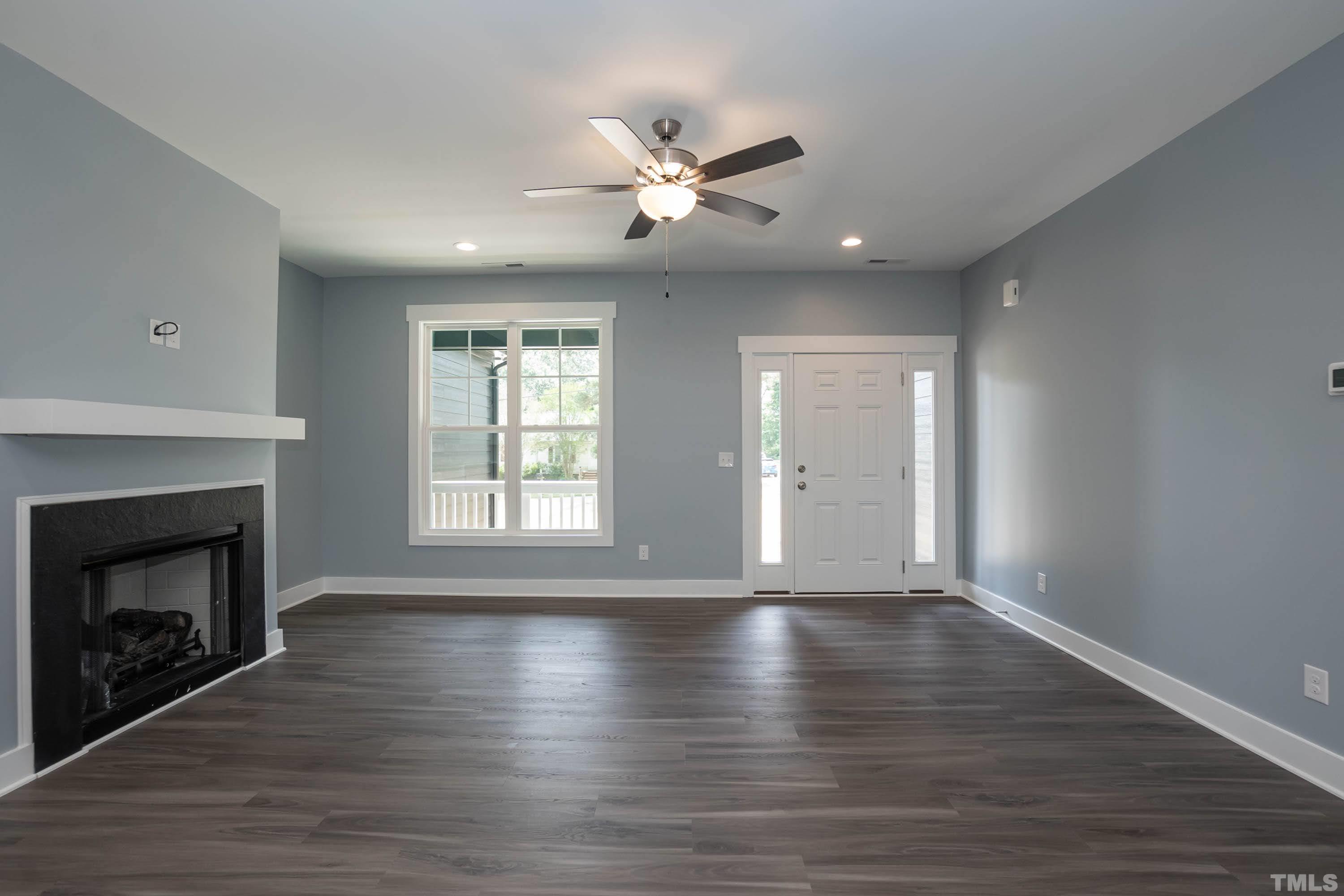 1701 Honeysuckle Road Raleigh, NC 27609 - Photo 7 of 29 a view of an empty room with wooden floor fireplace and a window