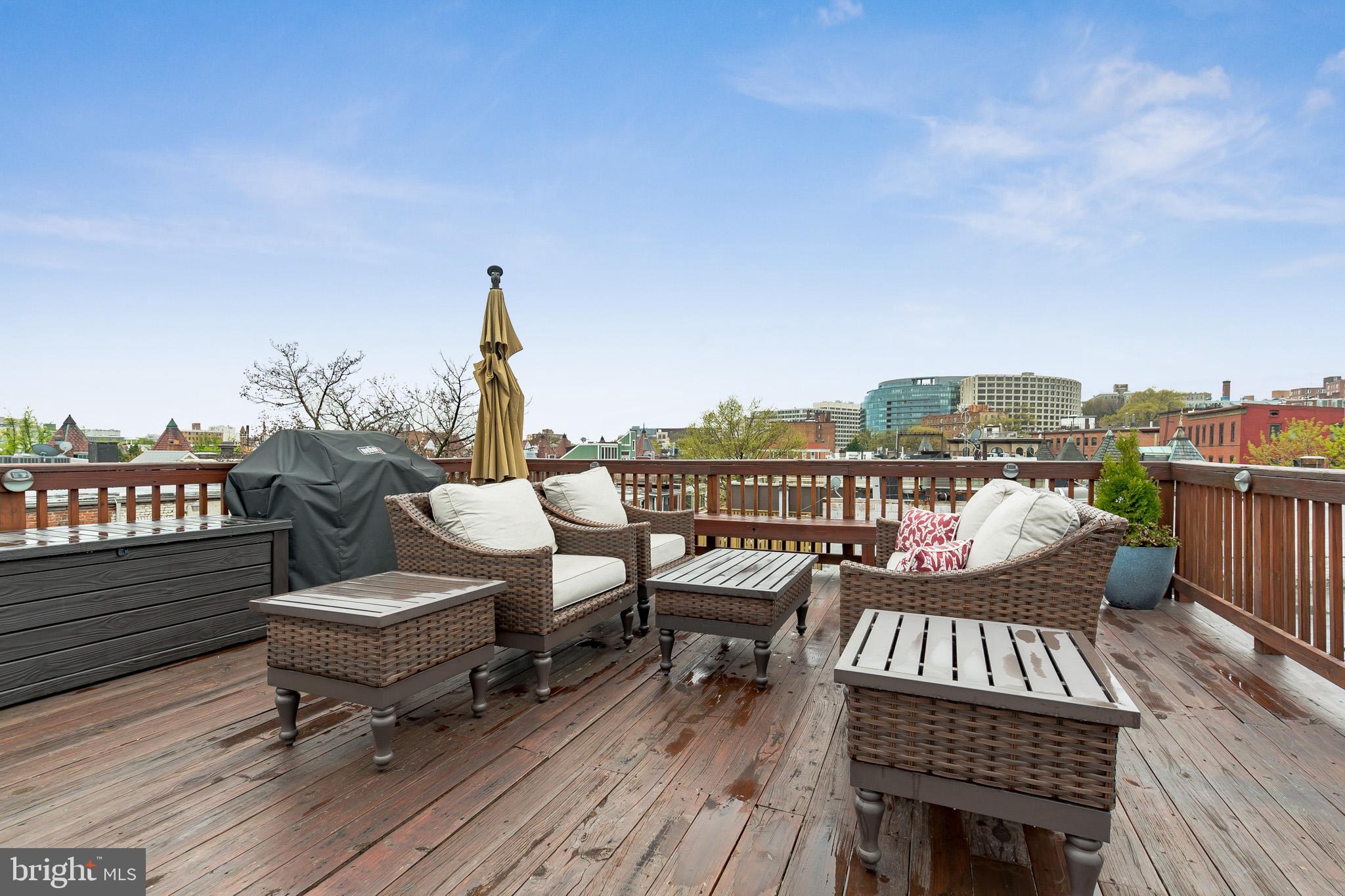 1754 Willard Street Northwest, Unit 2 Washington, DC 20009 - Photo 20 of 28 a view of a roof deck with table and chairs a barbeque with wooden floor and fence