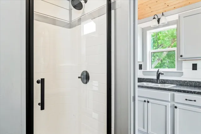 a bathroom with a granite countertop sink and mirror next to a window