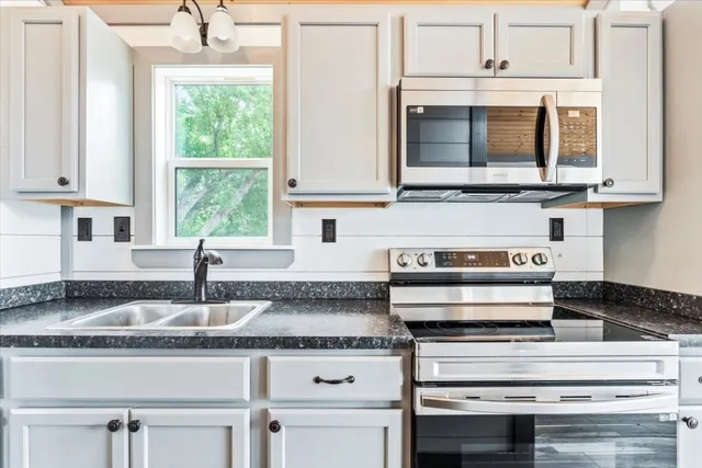 a kitchen with granite countertop a stove and white cabinets