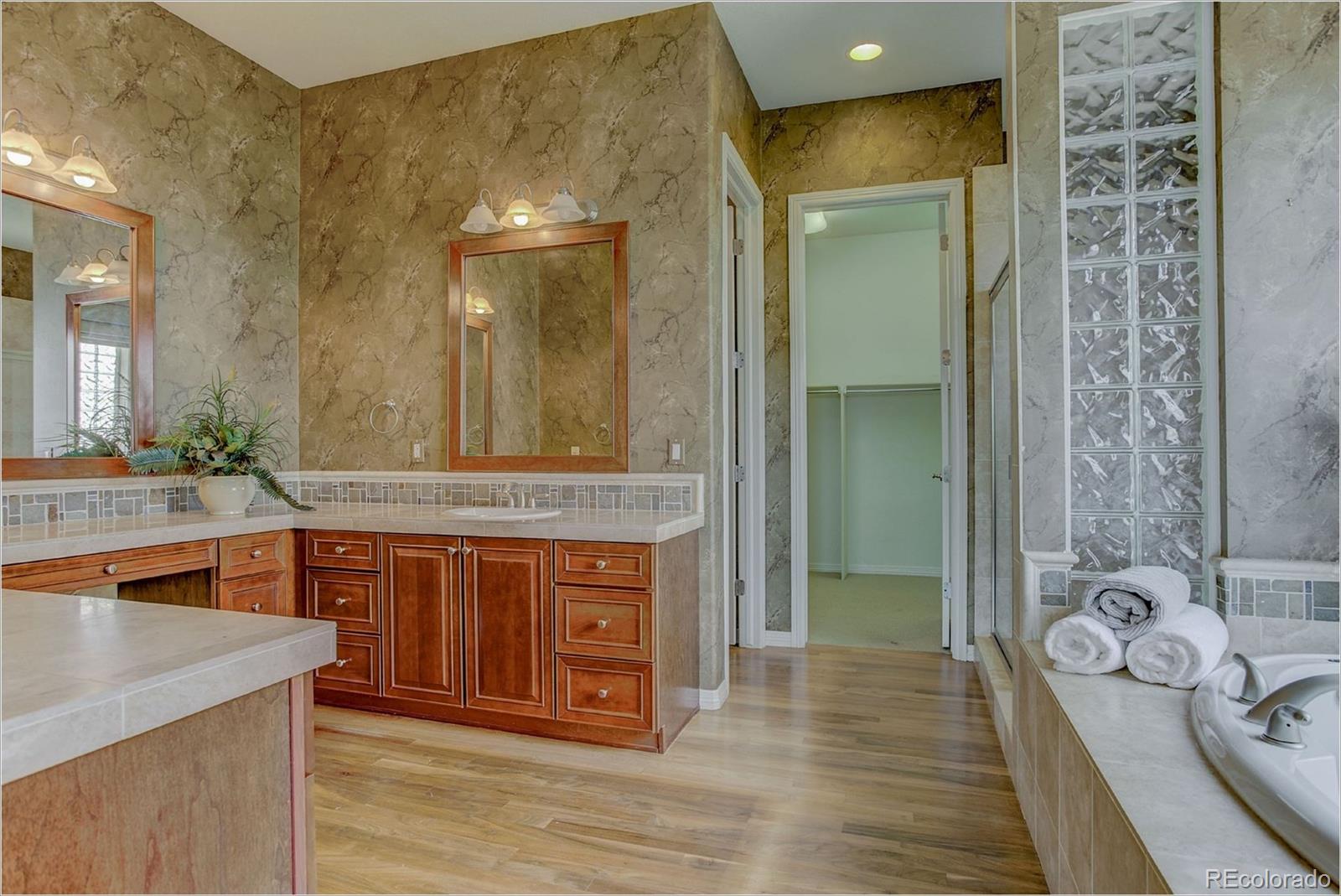 9061 Hunters Way Highlands Ranch, CO 80129 - Photo 22 of 33 a spacious bathroom with a granite countertop tub a double vanity sink and a mirror