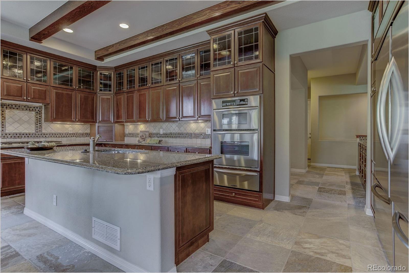 9061 Hunters Way Highlands Ranch, CO 80129 - Photo 6 of 33 a kitchen with granite countertop a sink and a refrigerator