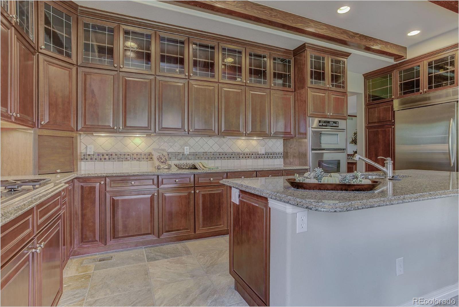 9061 Hunters Way Highlands Ranch, CO 80129 - Photo 7 of 33 a kitchen with stainless steel appliances granite countertop a sink and dishwasher a stove top oven with wooden floor